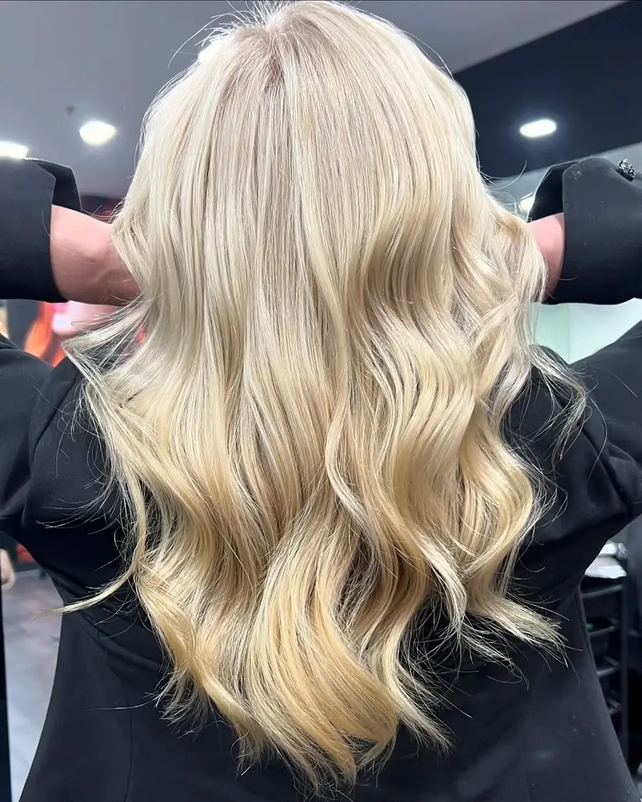 Long platinum blonde hair styled into loose waves after a full-head blonde
