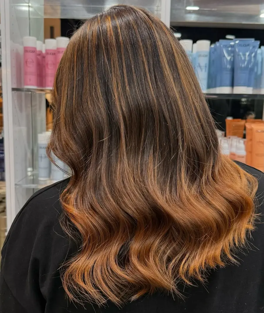 Mid-length hair melting from a dark root into warm copper balayage ends