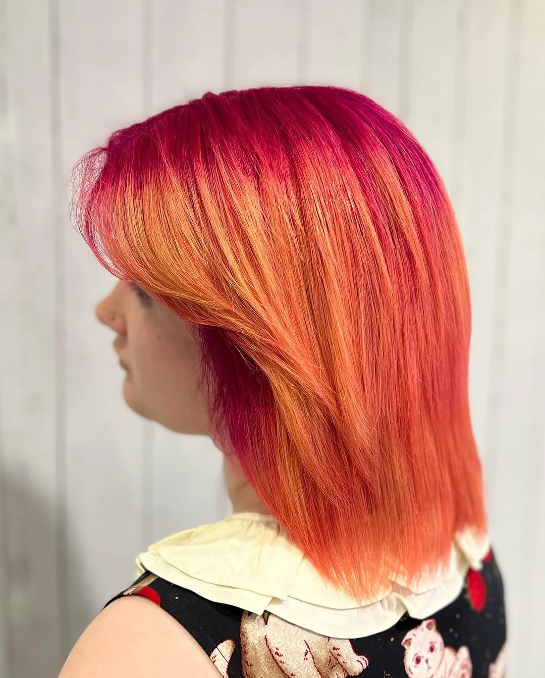 Chin-length bob melting from magenta at the roots into bright orange ends