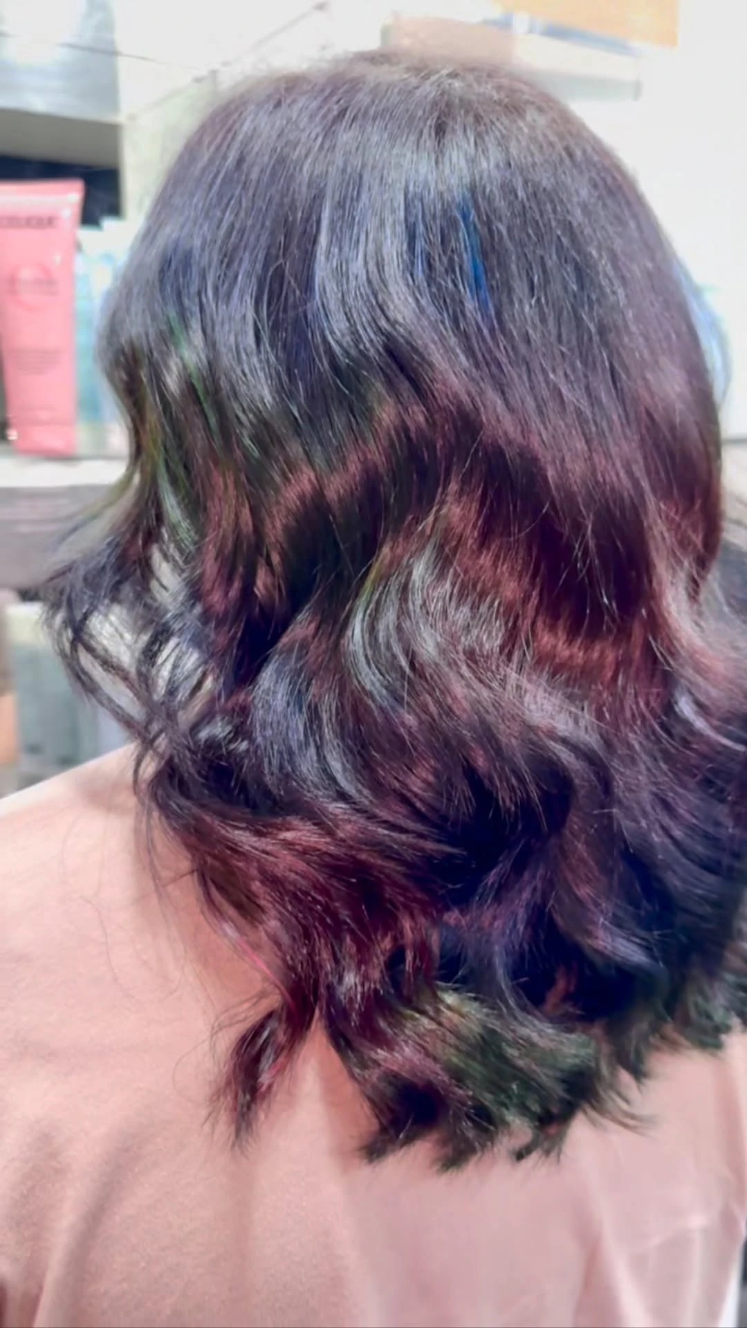 Shoulder-length hair coloured in a purple, teal and burgundy oil-slick blend