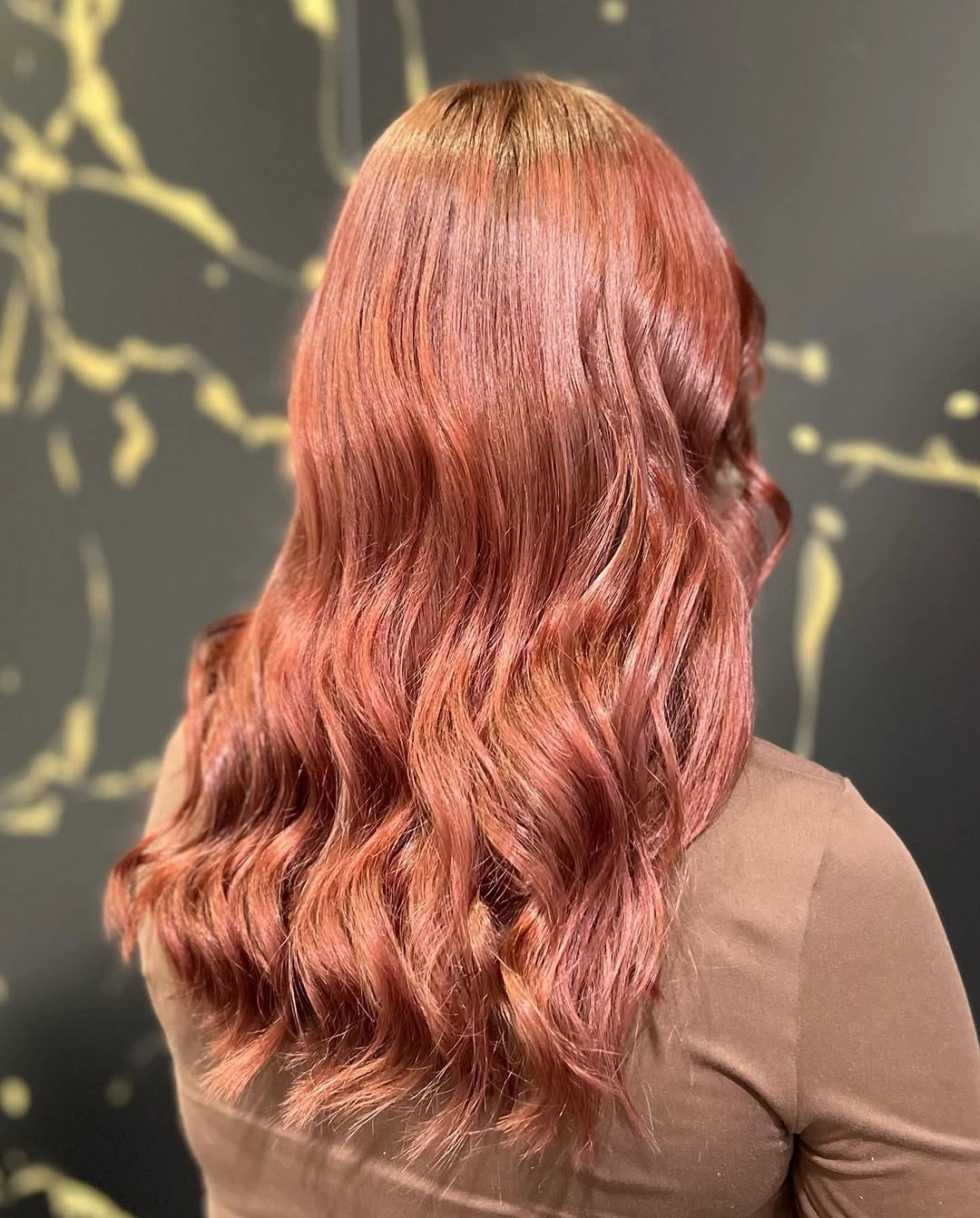 Shoulder-length rose-copper hair finished with a glossy wave