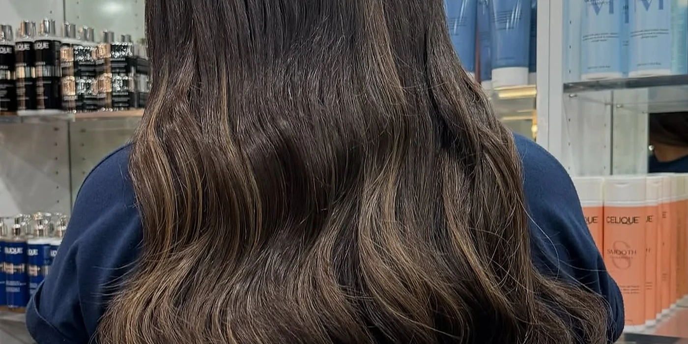Long brunette hair cut into soft layers and styled in loose waves