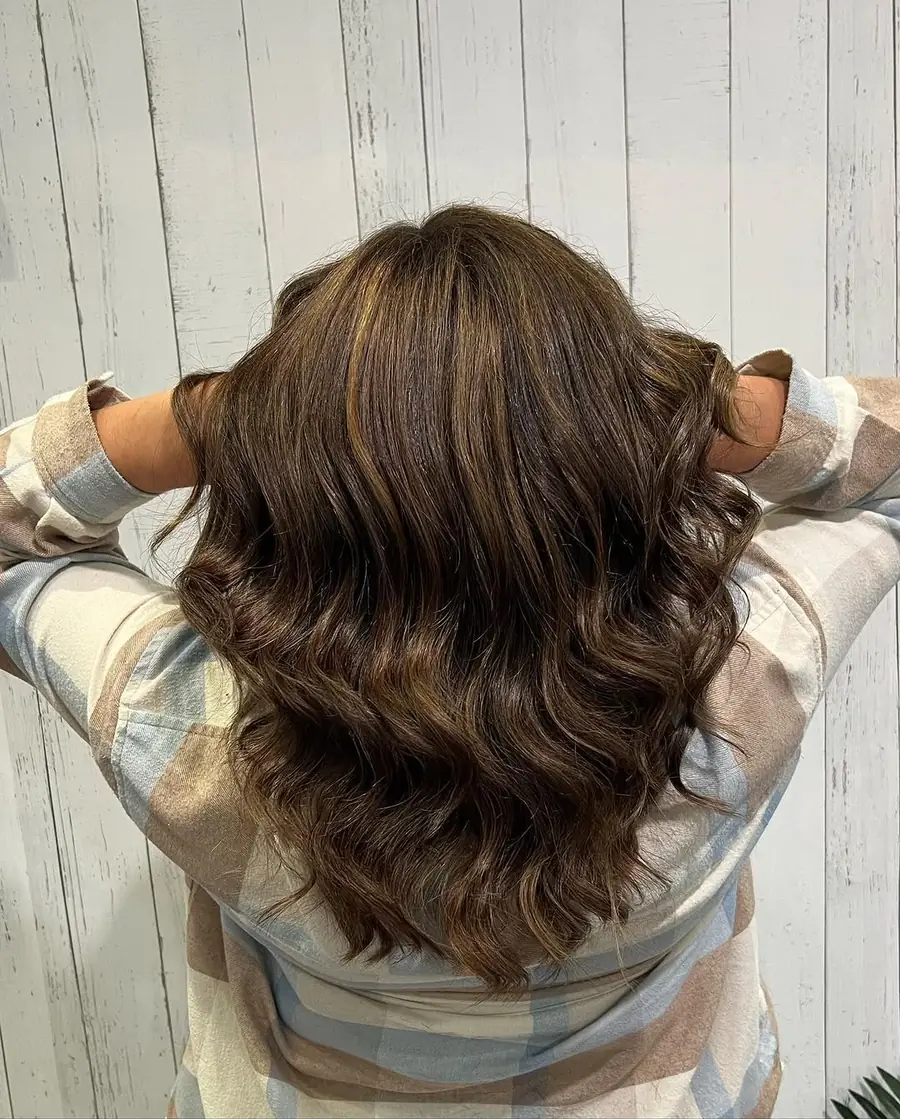 Shoulder-length brunette hair cut and styled into soft bouncy curls