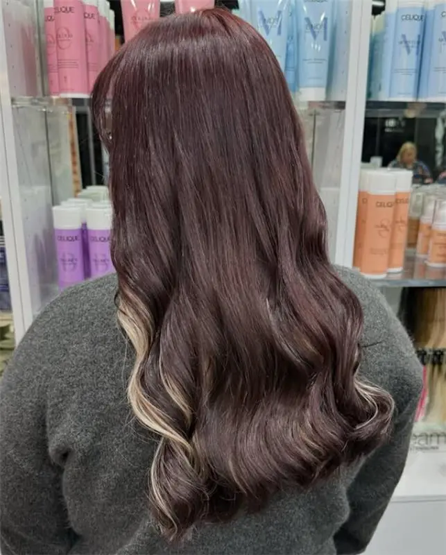 Long deep brunette hair styled in soft waves with subtle light face-framing pieces