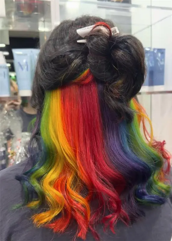 Long dark hair with a vivid rainbow underlayer styled in loose waves
