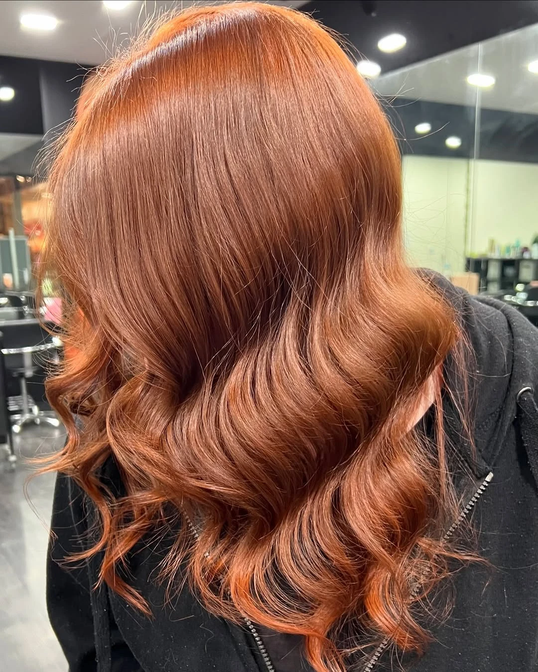 Shoulder-length bright copper hair styled into glossy waves